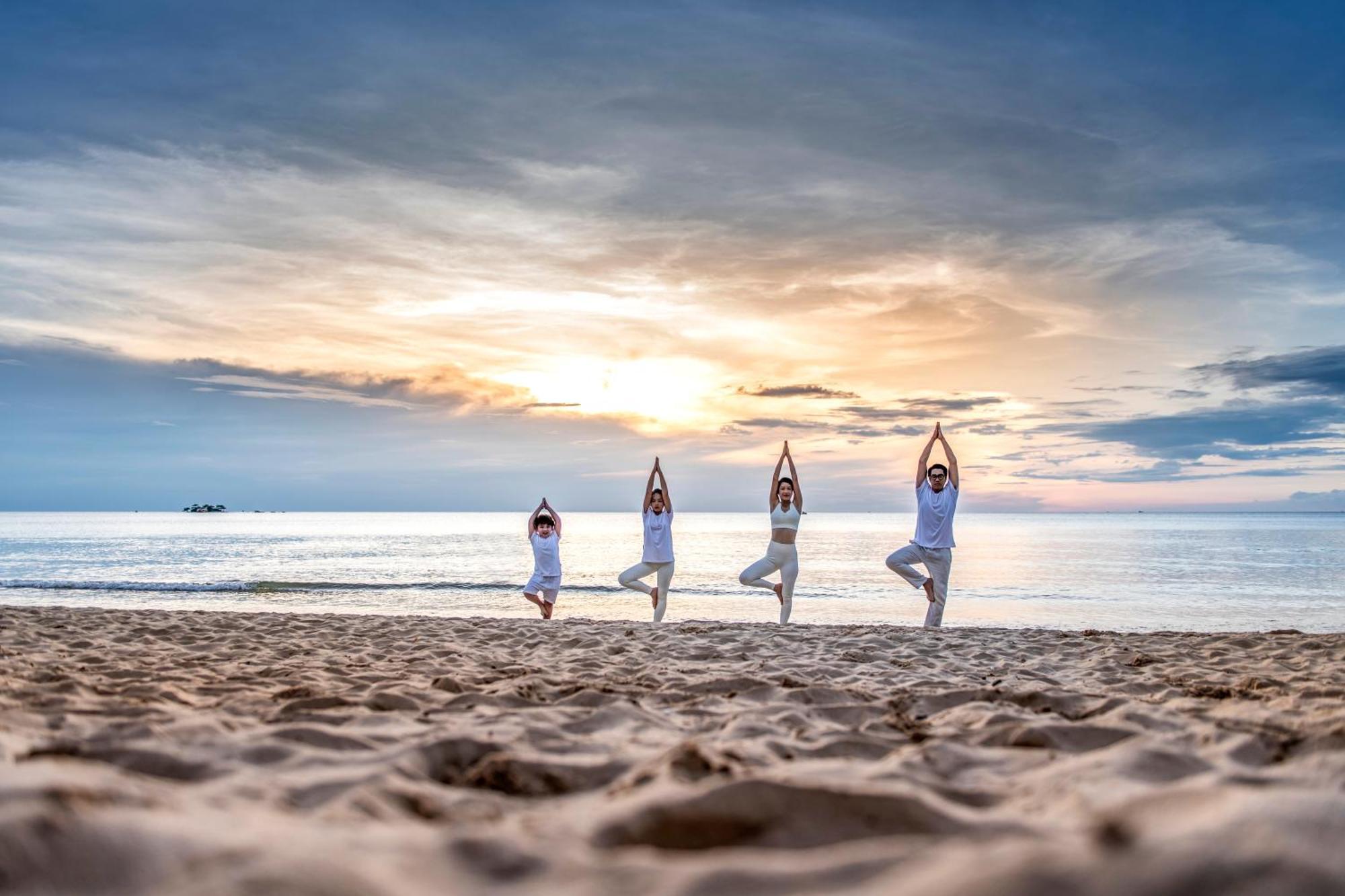 Vinpearl Resort & Spa Phu Quoc Dış mekan fotoğraf Family practicing yoga on the beach